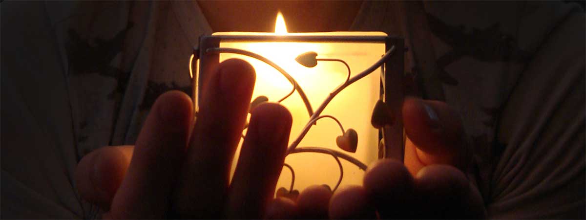 hands touch a candle holder in the dark