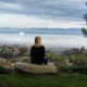 woman sitting on boulder looking out over the misty valley